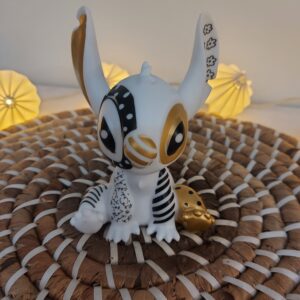 Figurine Stitch sans marque en plastique blanc ornée de motifs noirs et dorés style art toy